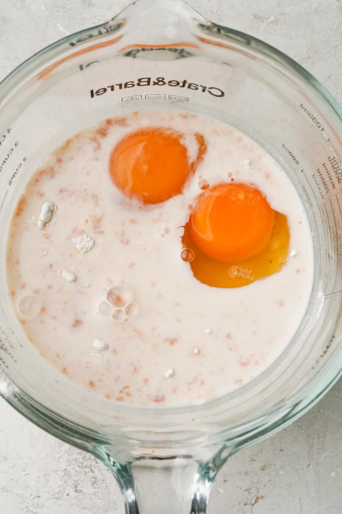 eggs added to German pancake batter in a measuring cup