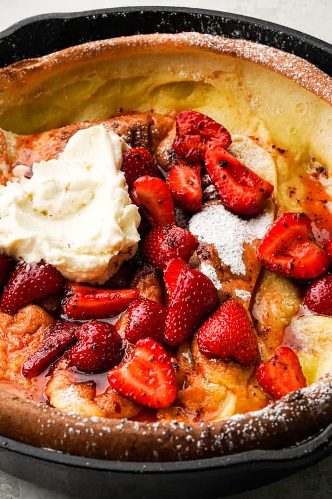 close up view of a strawberry dutch baby in a cast iron skillet