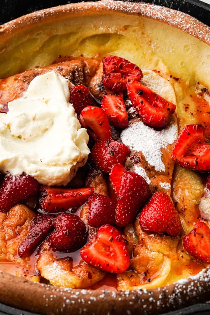 close up view of strawberry dutch baby in a cast iron skillet