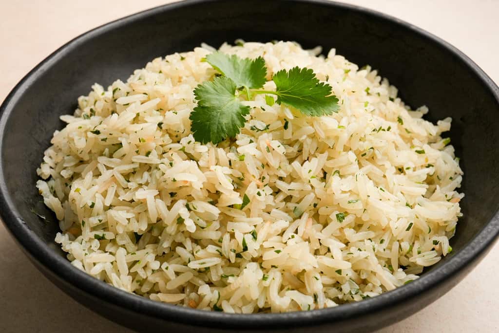 a bowl of cilantro lime rice garnished with cilantro leaves