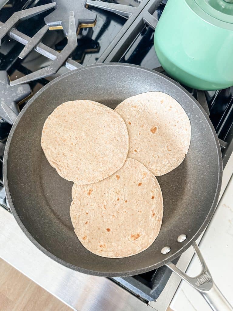 tortillas being warmed on the stovetop 