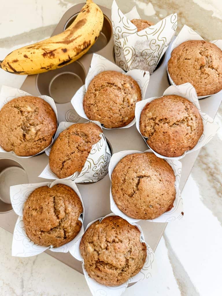banana bread muffin in the muffin tin with a banana on the side